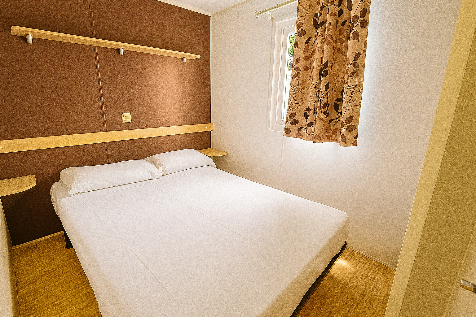 Cama doble en bungalow del Camping Mola Surf Loredo con luz natural y estilo acogedor