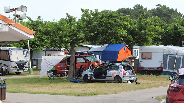 Parcela de 30 metros cuadrados con furgoneta camper estacionada, rodeada de árboles, con conexión eléctrica y servicios comunes en Camping Mola! Surf Loredo.