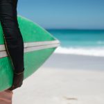 Surfista sujetando una tabla en la playa de Loredo antes de surfear