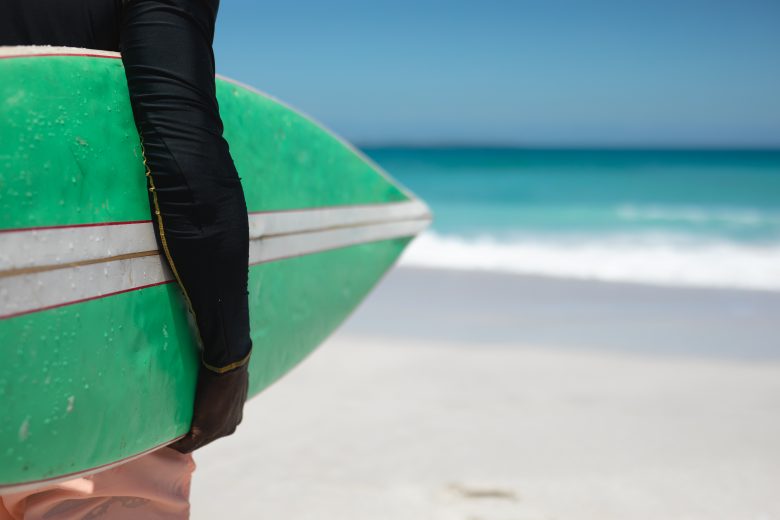 Surfista sujetando una tabla en la playa de Loredo antes de surfear