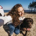 Mujer disfrutando de un día de playa con su perro durante unas vacaciones en Cantabria