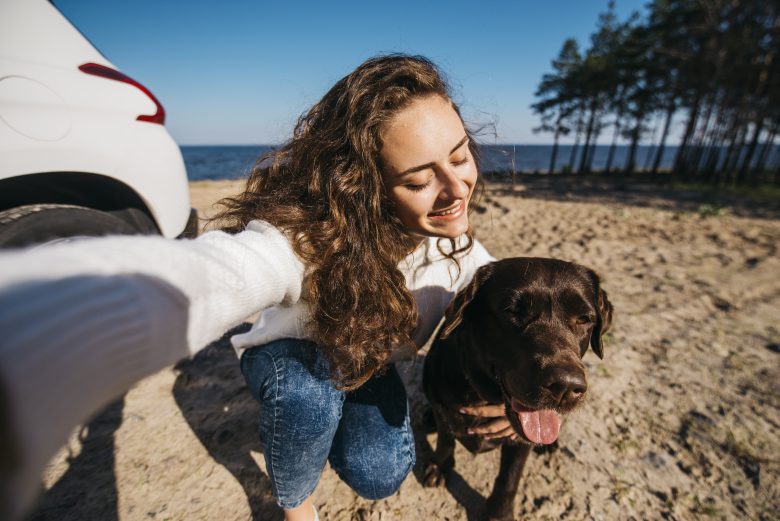 Mujer disfrutando de un día de playa con su perro durante unas vacaciones en Cantabria