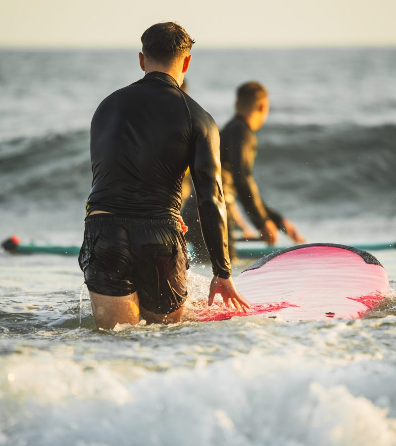 Two unrecognizable young men at the beach with their surfboards.